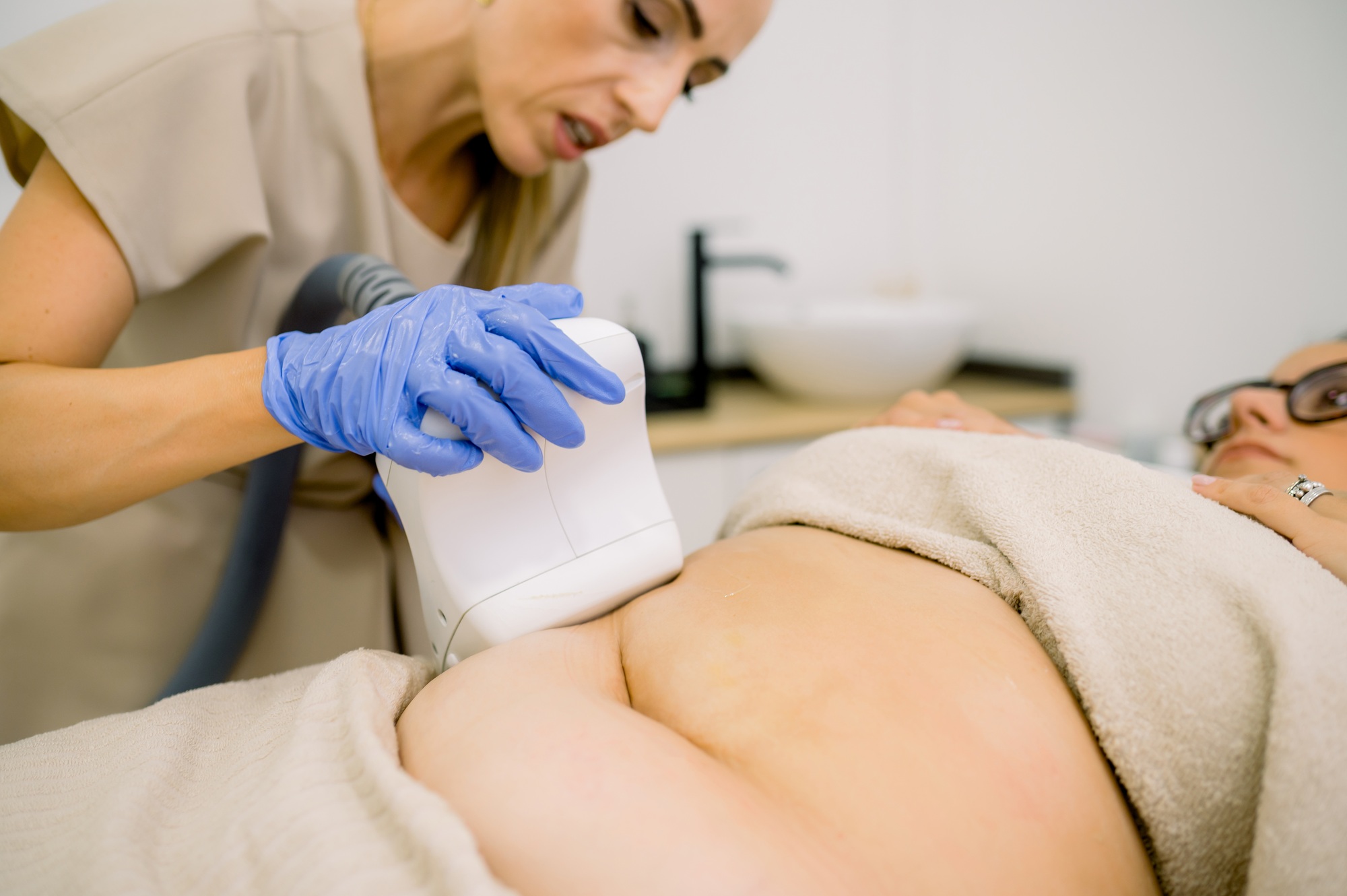 Cosmetician giving fat reducing treatment for client