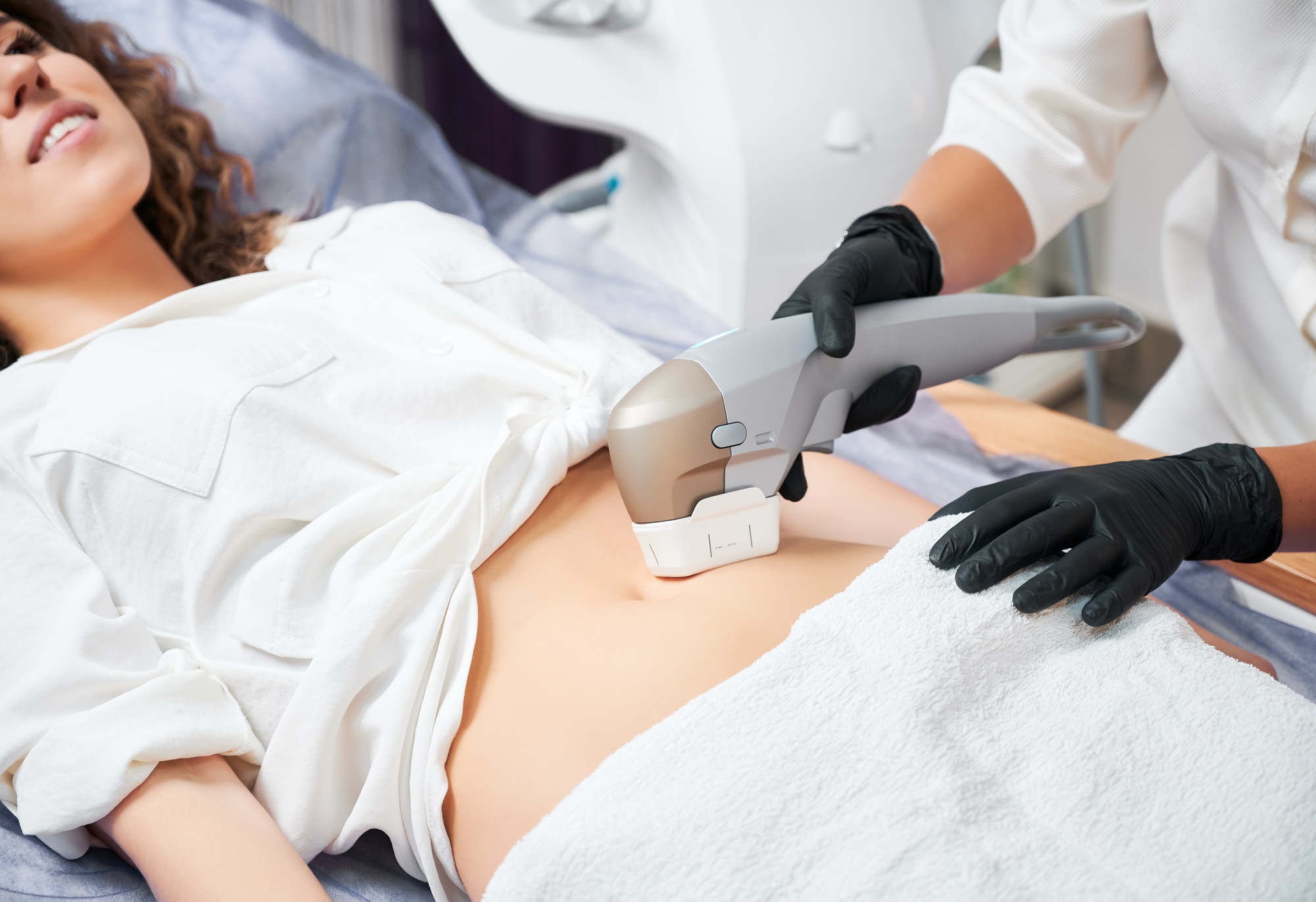 Young woman receiving body lifting and tightening treatment in clinic.